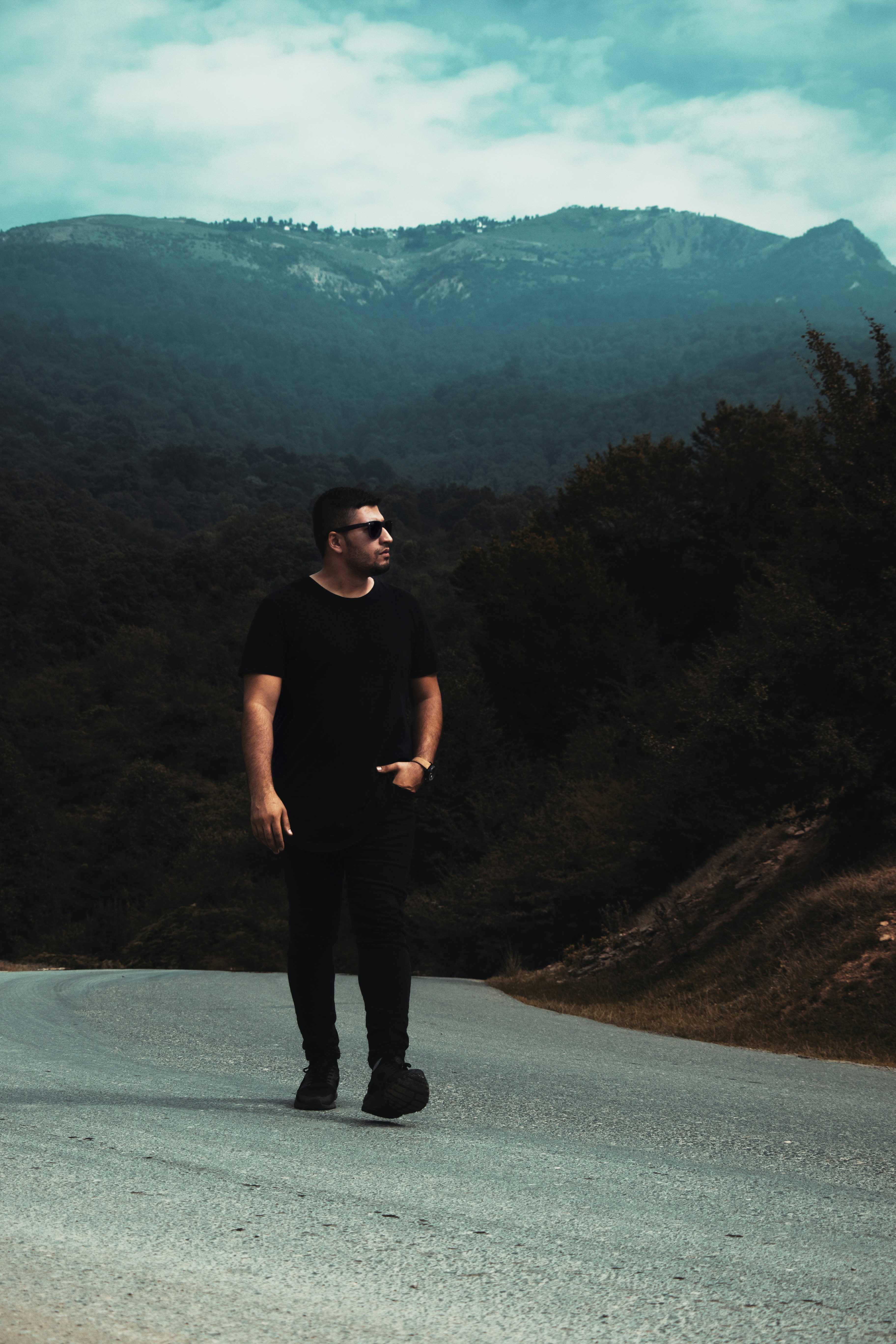 man in black tank top standing on road