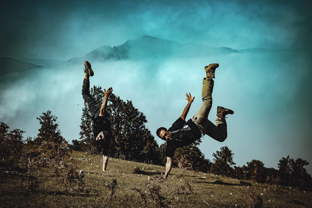 2 men jumping on green grass field during daytime