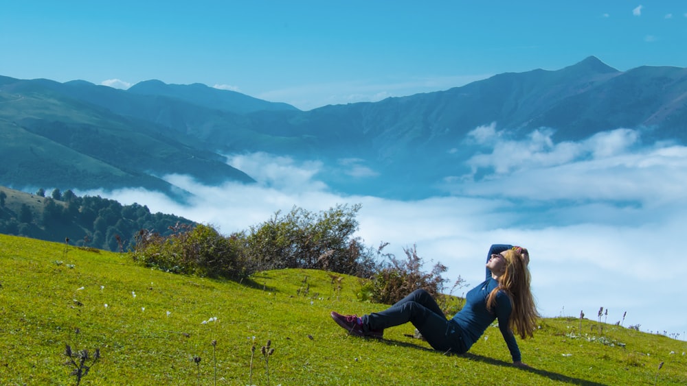 woman in black jacket sitting on green grass field during daytime