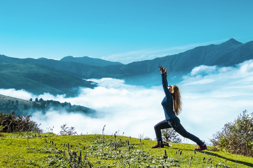 woman in black tank top and black leggings doing yoga on green grass field during daytime