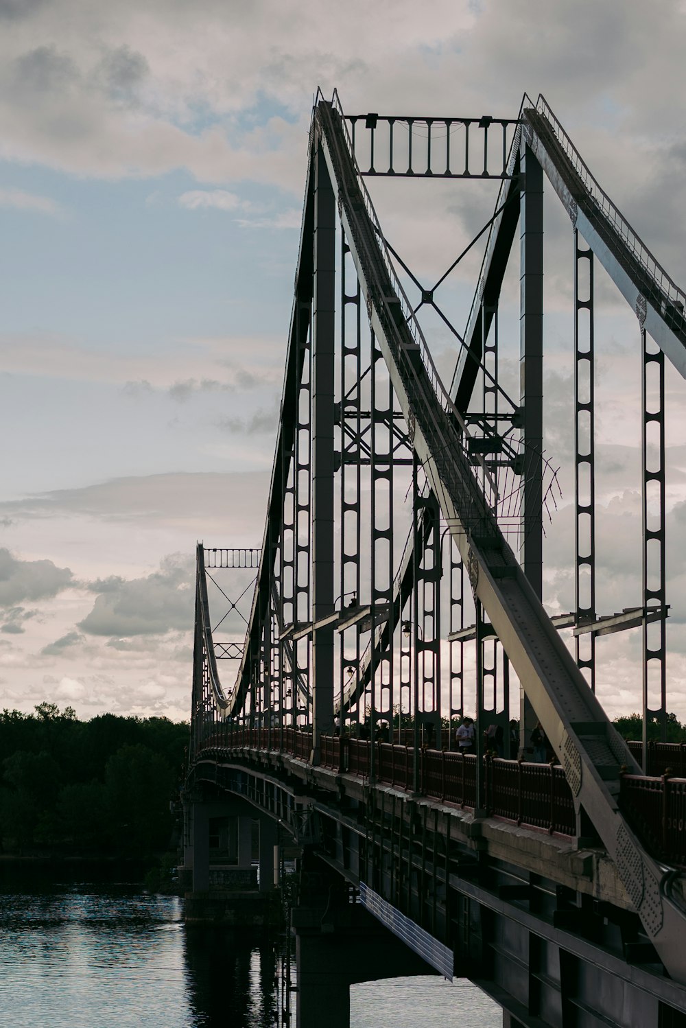 graue Metallbrücke über grüne Bäume tagsüber