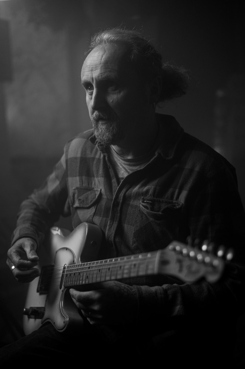 man in plaid shirt playing electric guitar