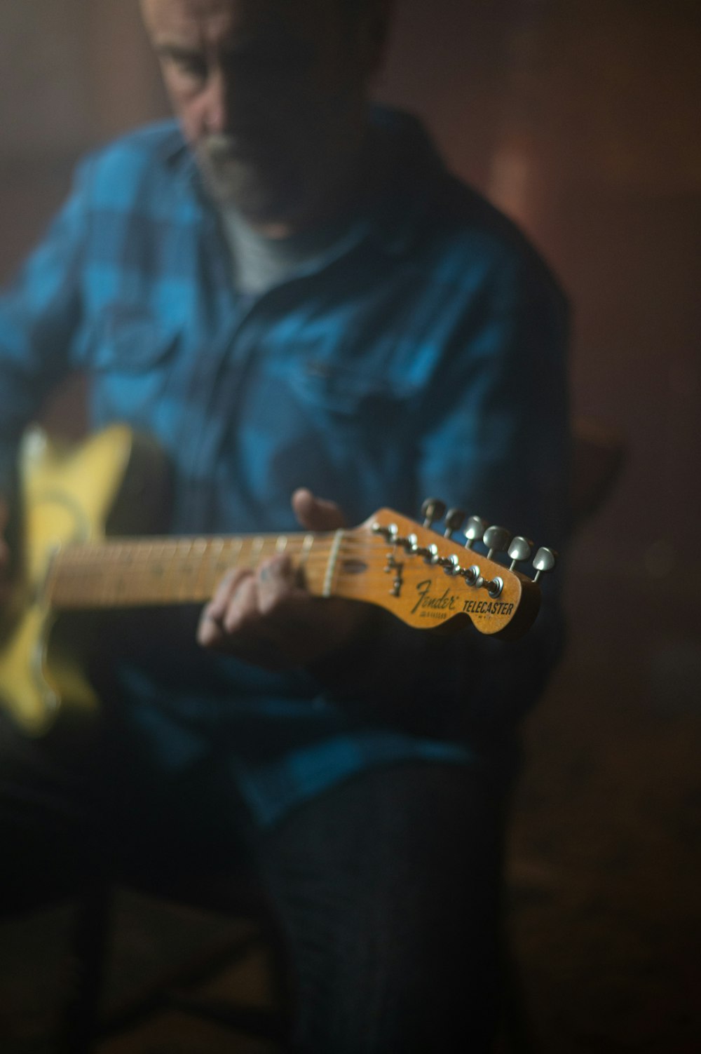 man in blue button up shirt playing electric guitar