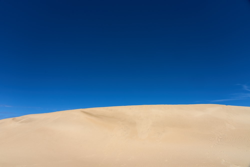 A sand dune under a blue sky photo – Free Nature Image on Unsplash