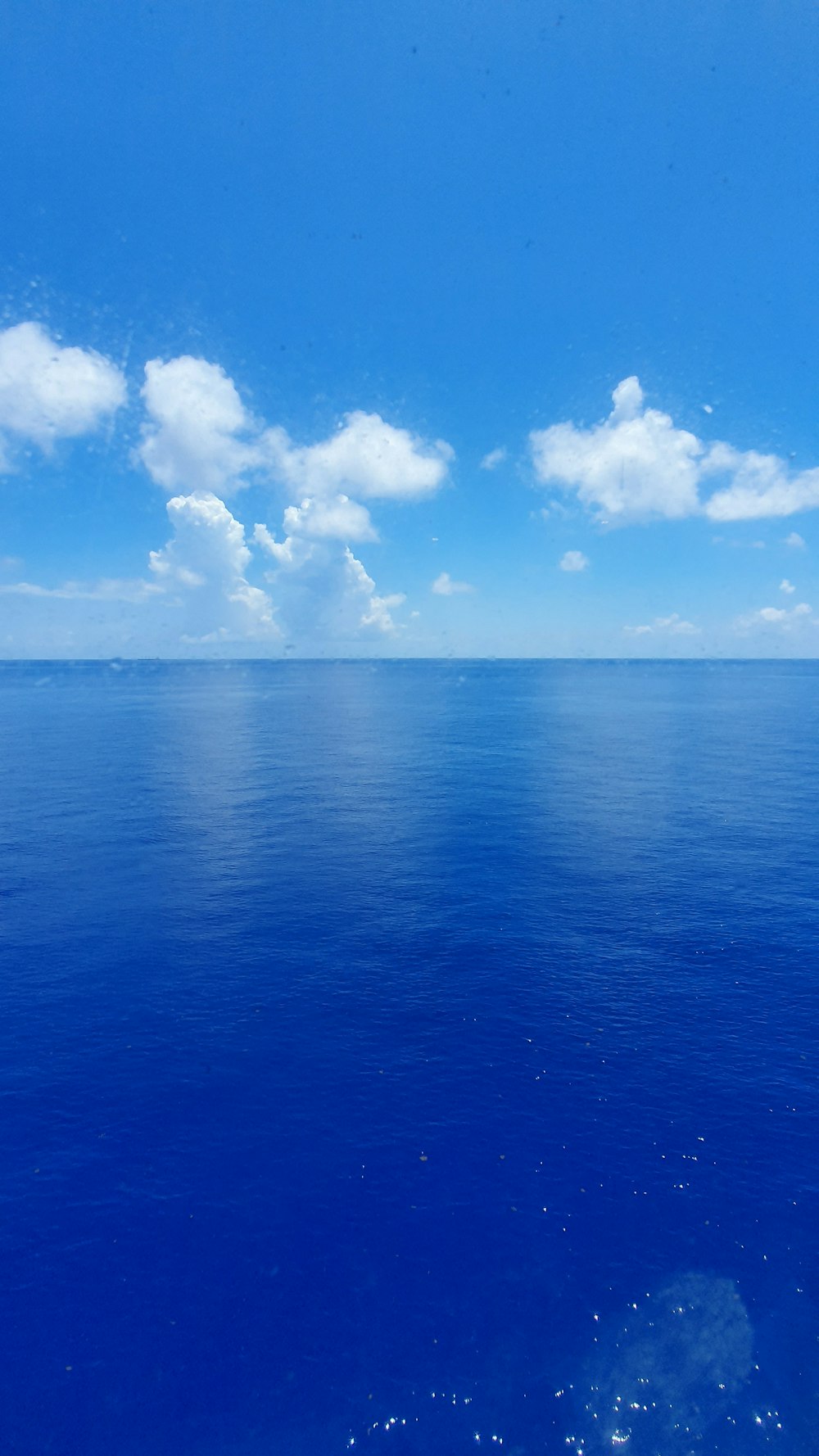 blue ocean under blue sky and white clouds during daytime