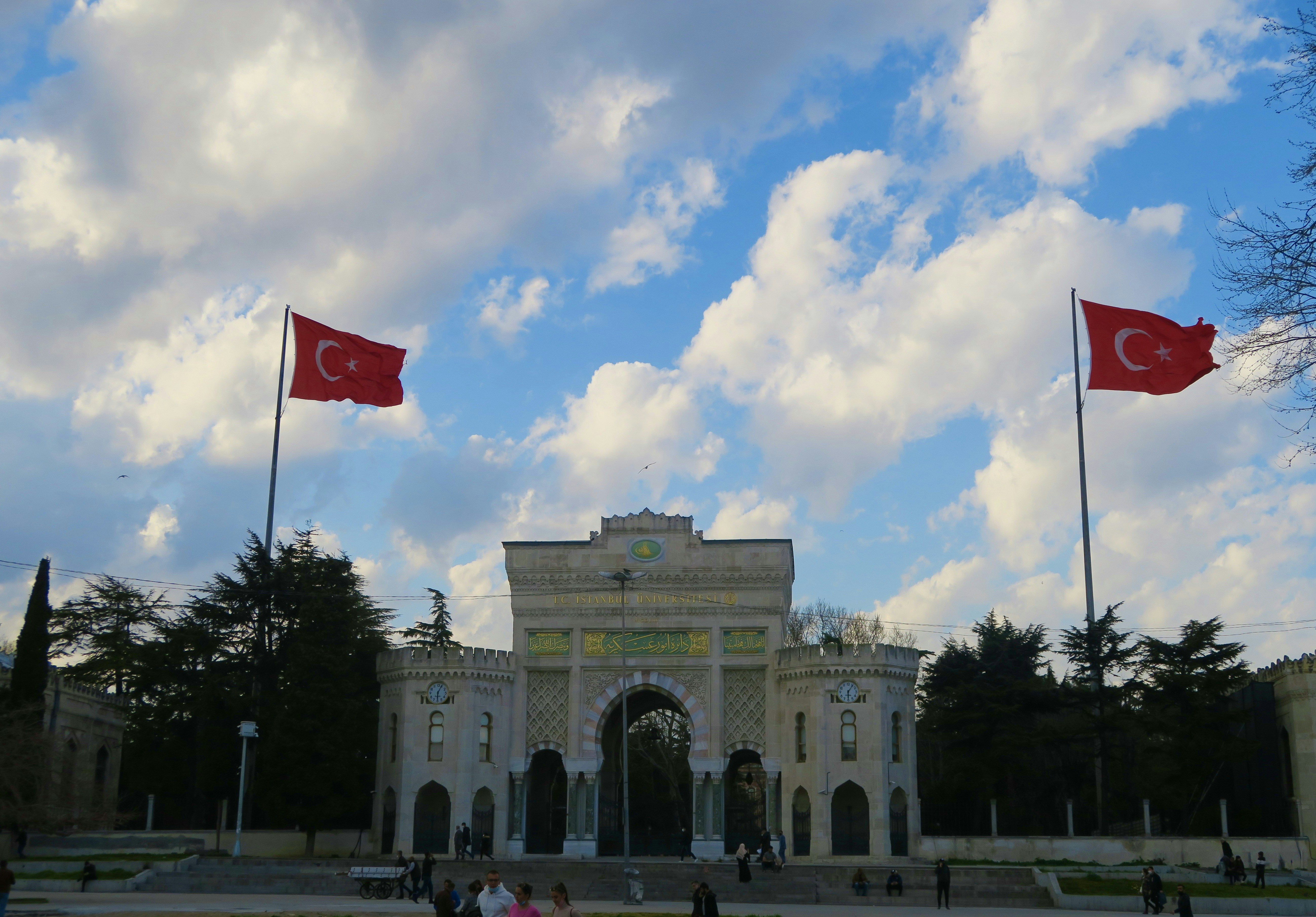 white concrete building with red flag on top under blue sky during daytime