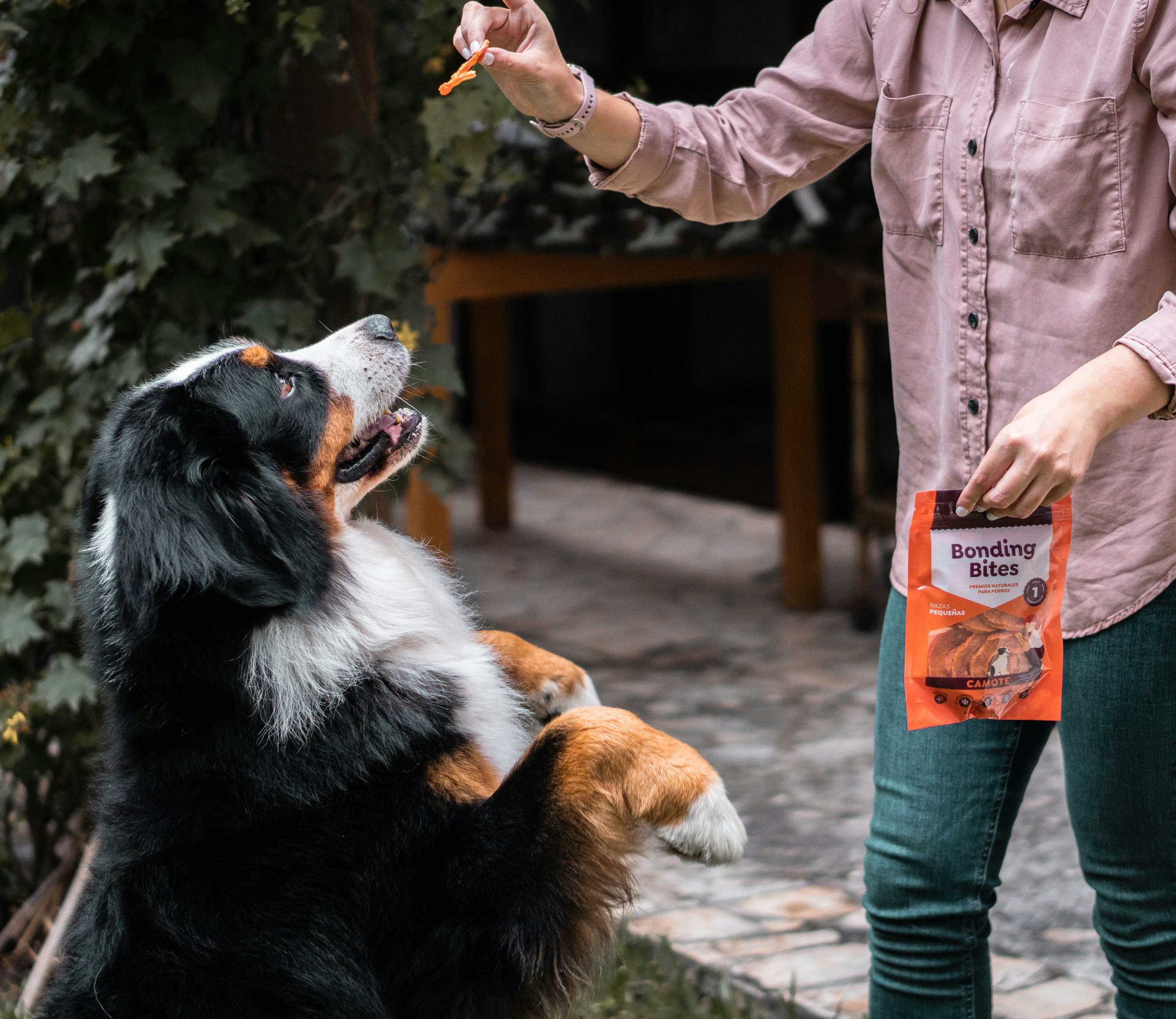 woman in pink jacket holding orange and black labeled pack
