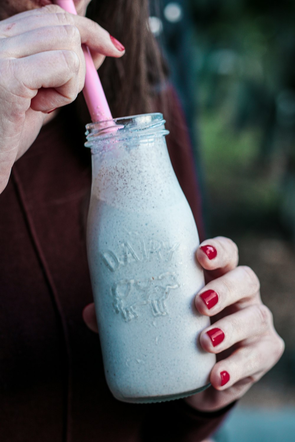 person holding clear glass bottle with white liquid