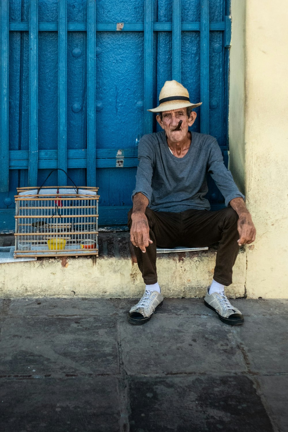 man in blue long sleeve shirt and brown pants sitting on blue wooden bench