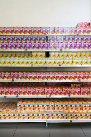 Shelves are stocked with colorful packaged juices, arranged neatly in rows with vibrant labels. Each row contains a different flavor, dominated by colors like purple, red, and yellow. These packages appear to be well-organized, likely in a supermarket or store setting.