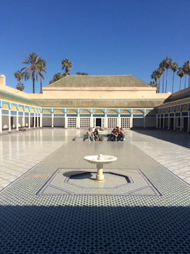 A serene courtyard with geometric Islamic patterns and students engaging in group study.