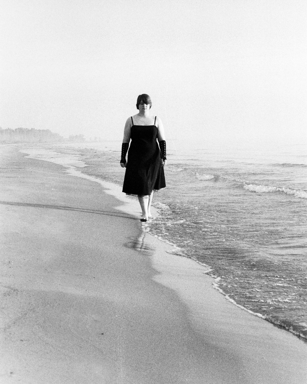 woman in black dress walking on beach