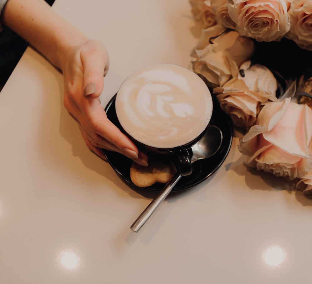 person holding white ceramic plate with white and pink rose