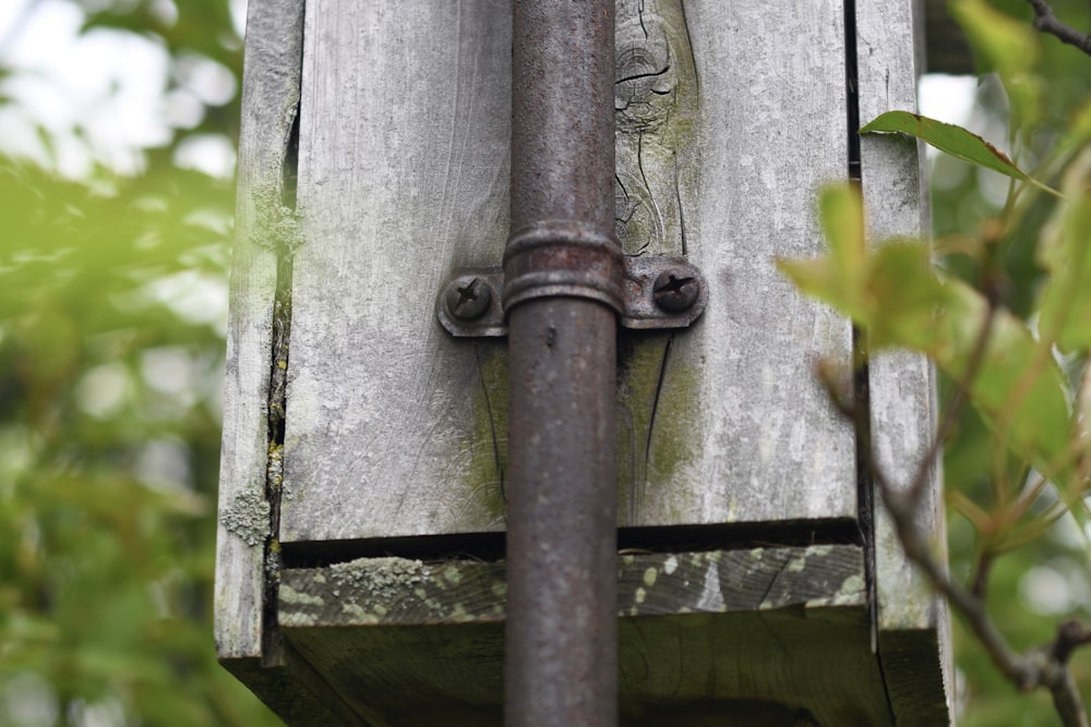 tubo de metal marrom no poste de madeira cinzento
