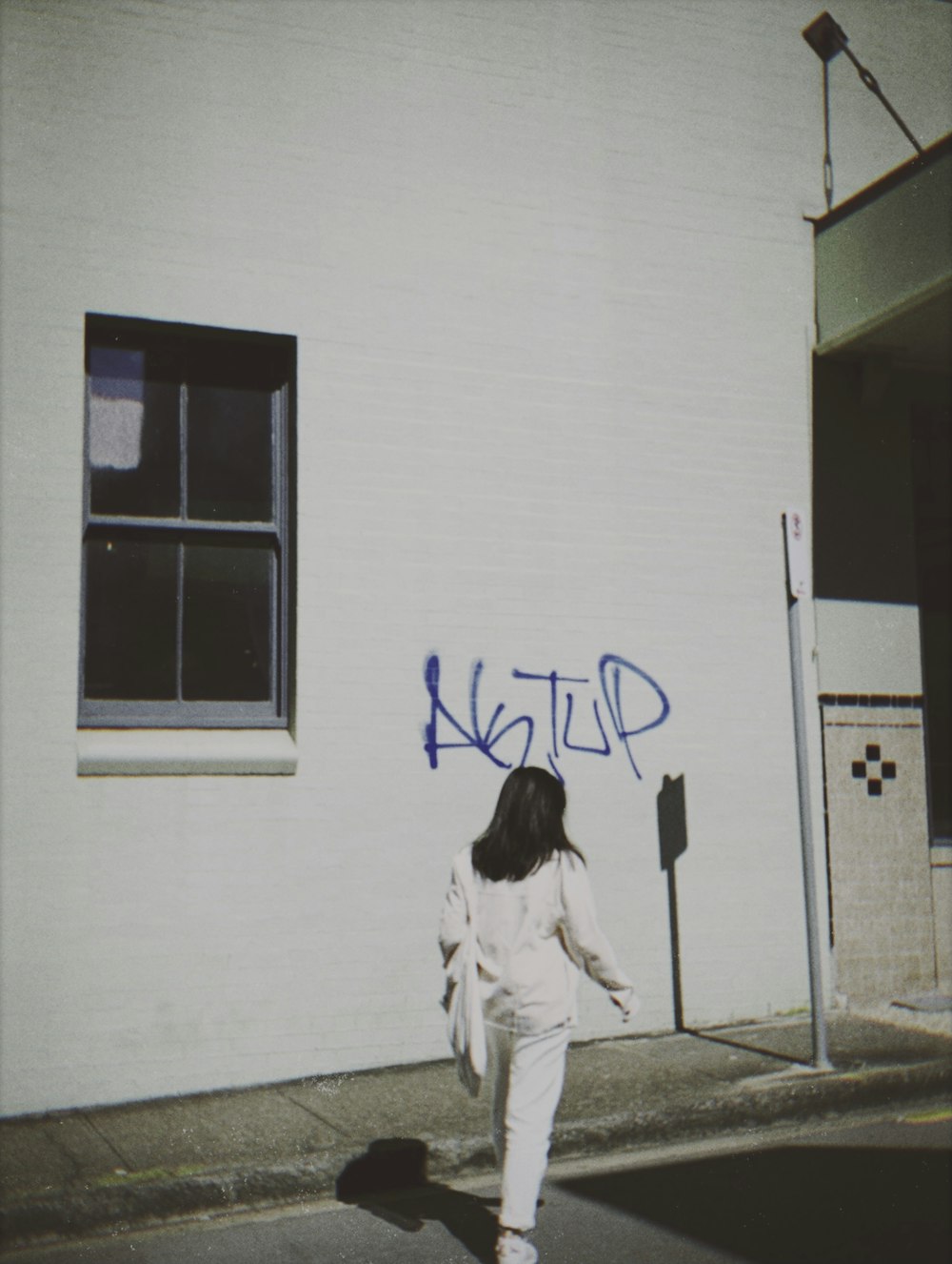 woman in white jacket standing near white wall