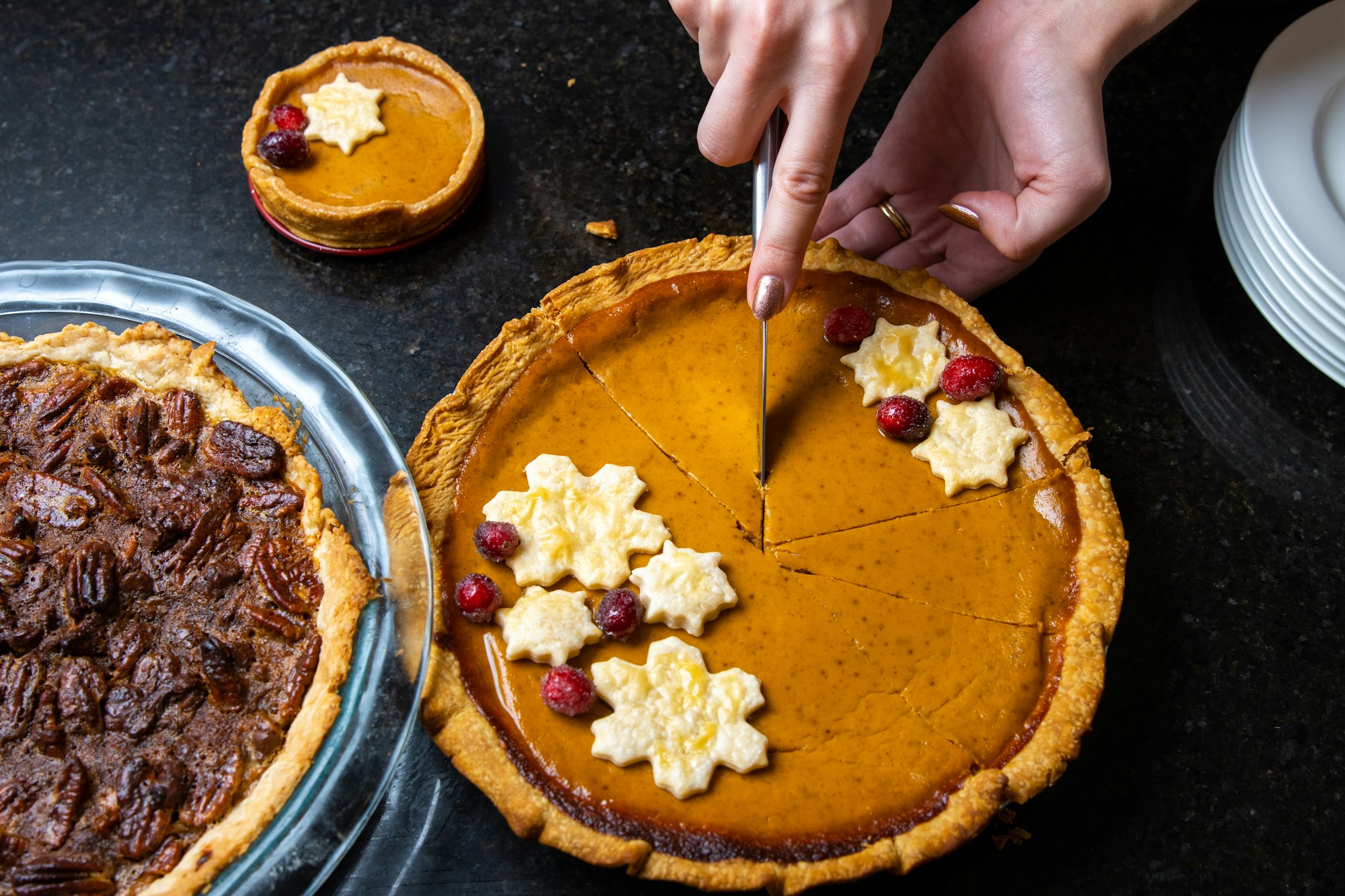 person slicing pie on stainless steel tray