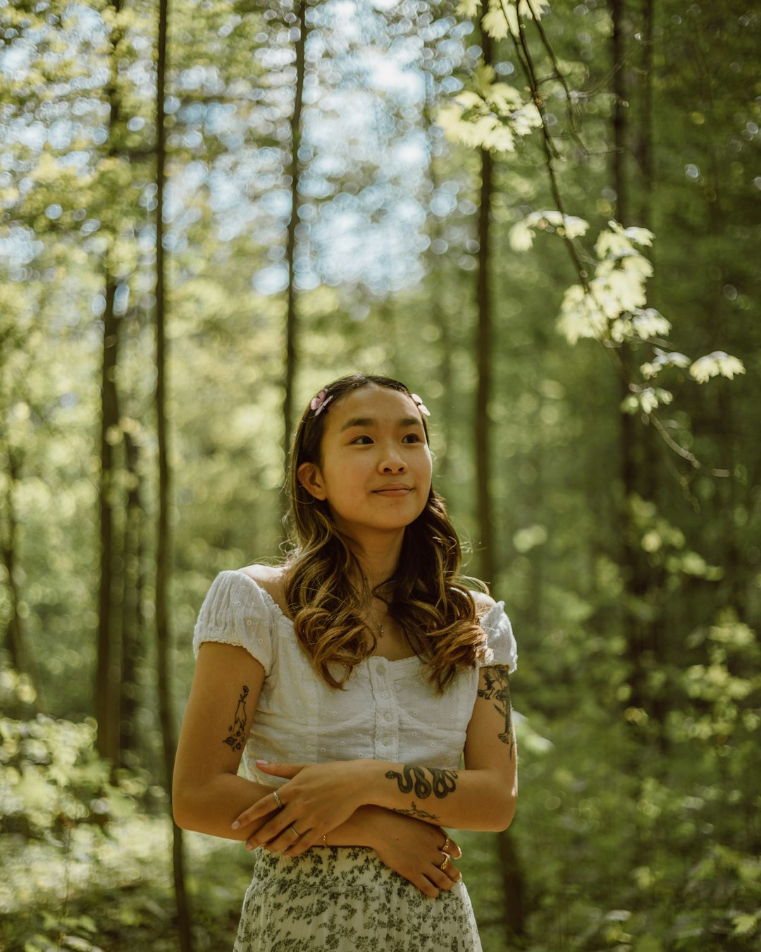 woman in white shirt standing in forest during daytime