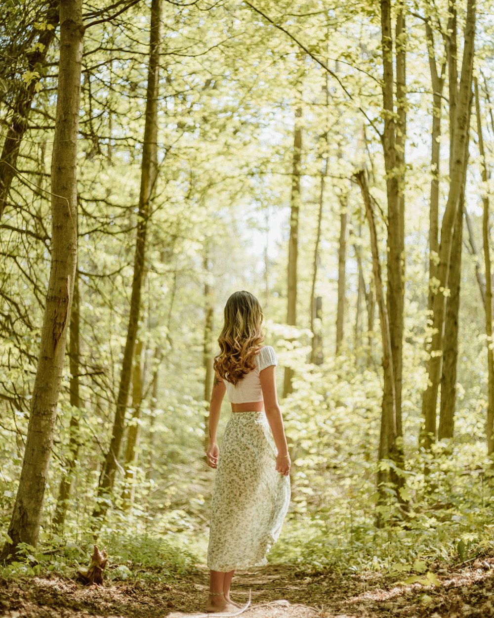 woman in white dress standing in the woods during daytime