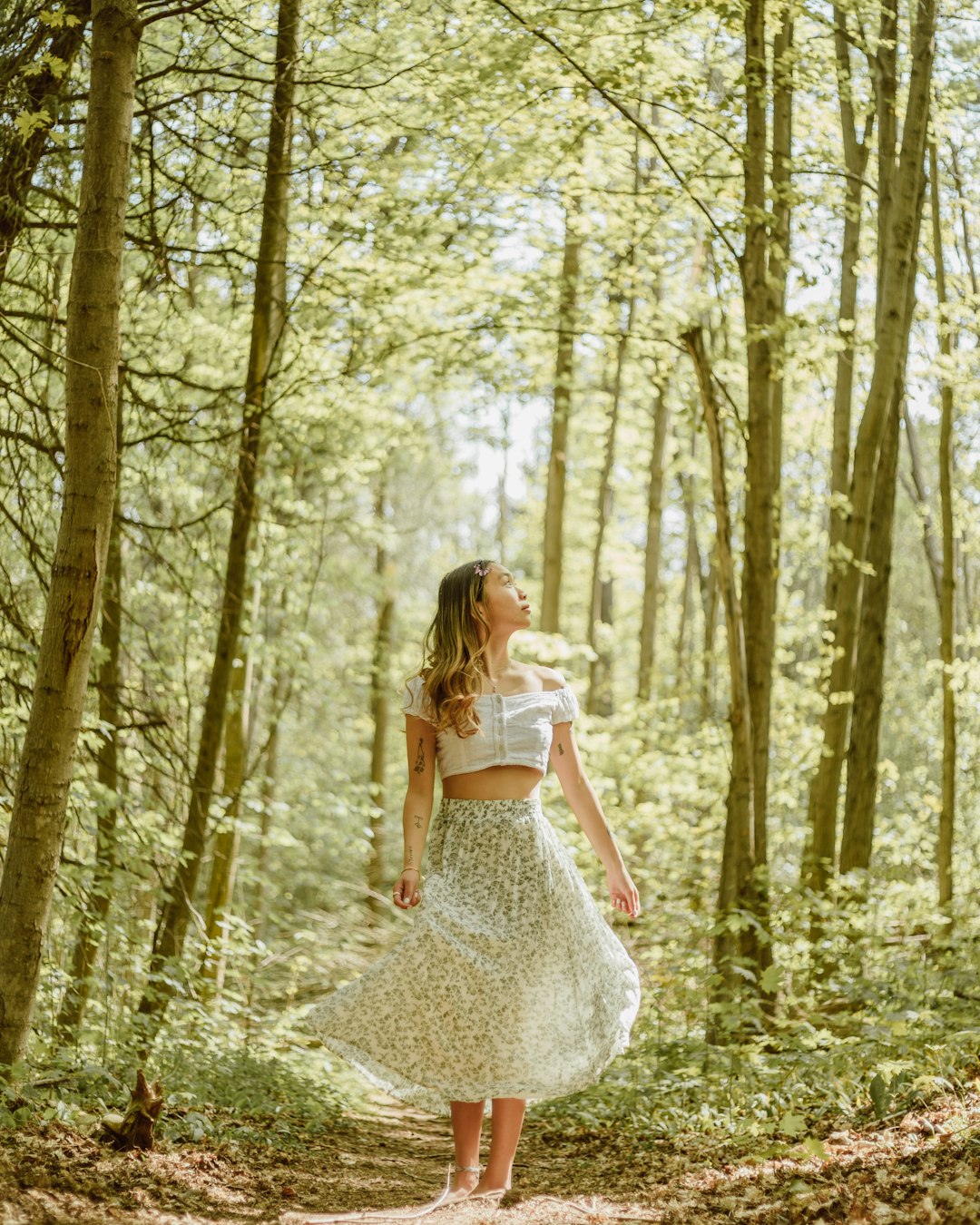 woman in white floral dress standing in the woods
