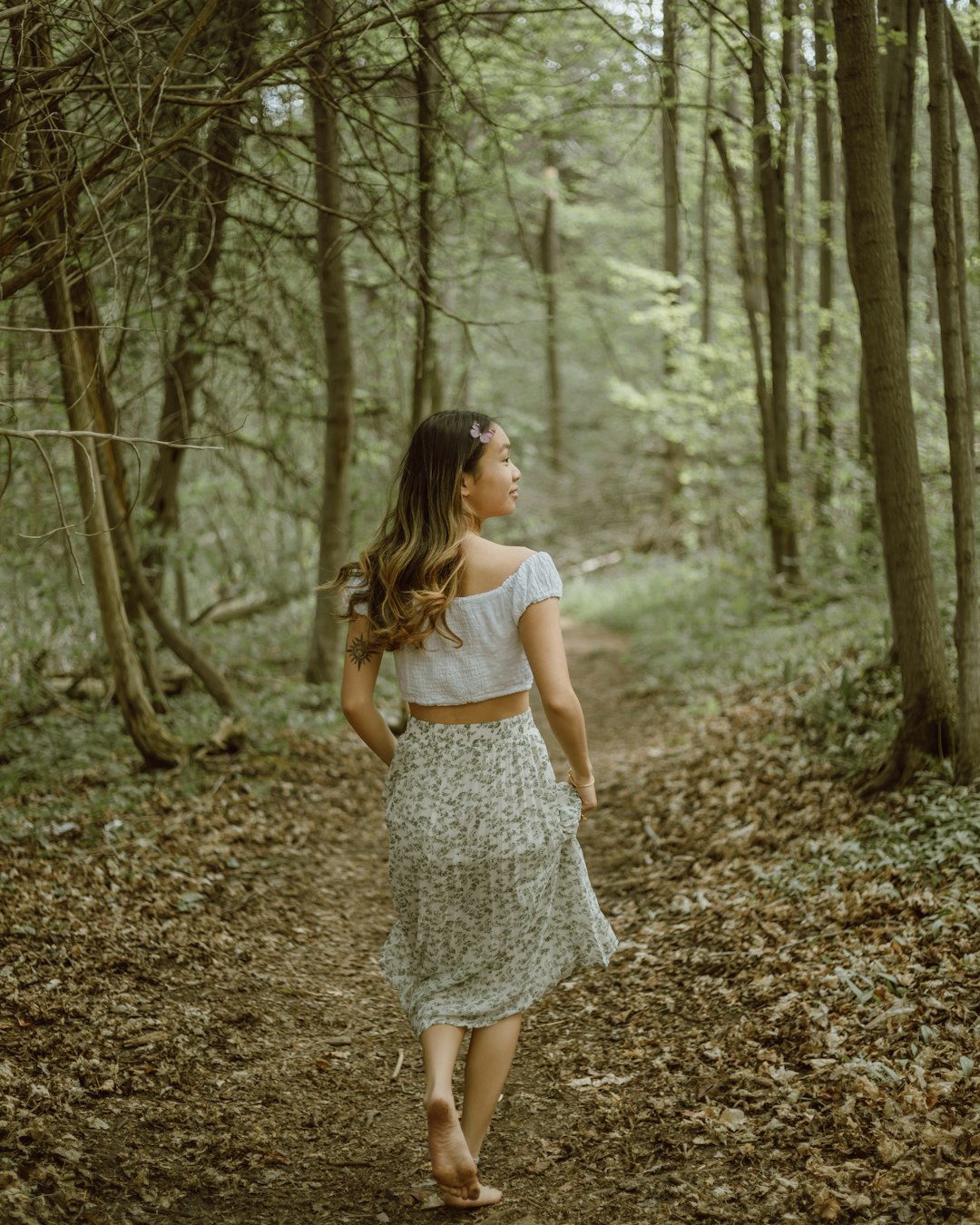 woman in white sleeveless dress standing on forest during daytime