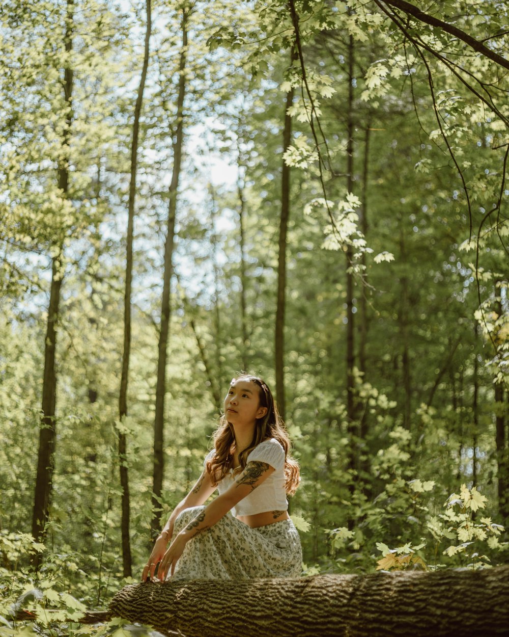 woman in white tank top and white floral skirt standing on forest during daytime