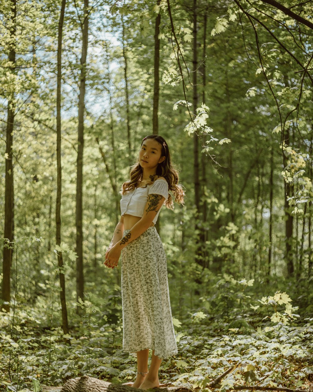 woman in white dress standing on forest during daytime