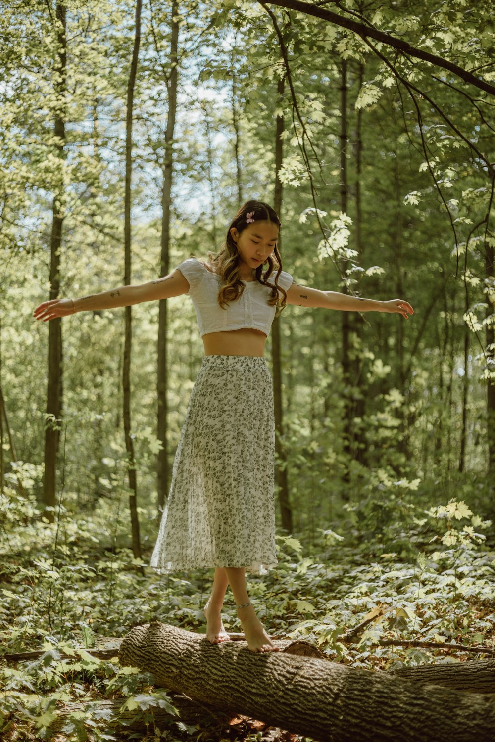 woman in white and black floral dress standing on forest during daytime
