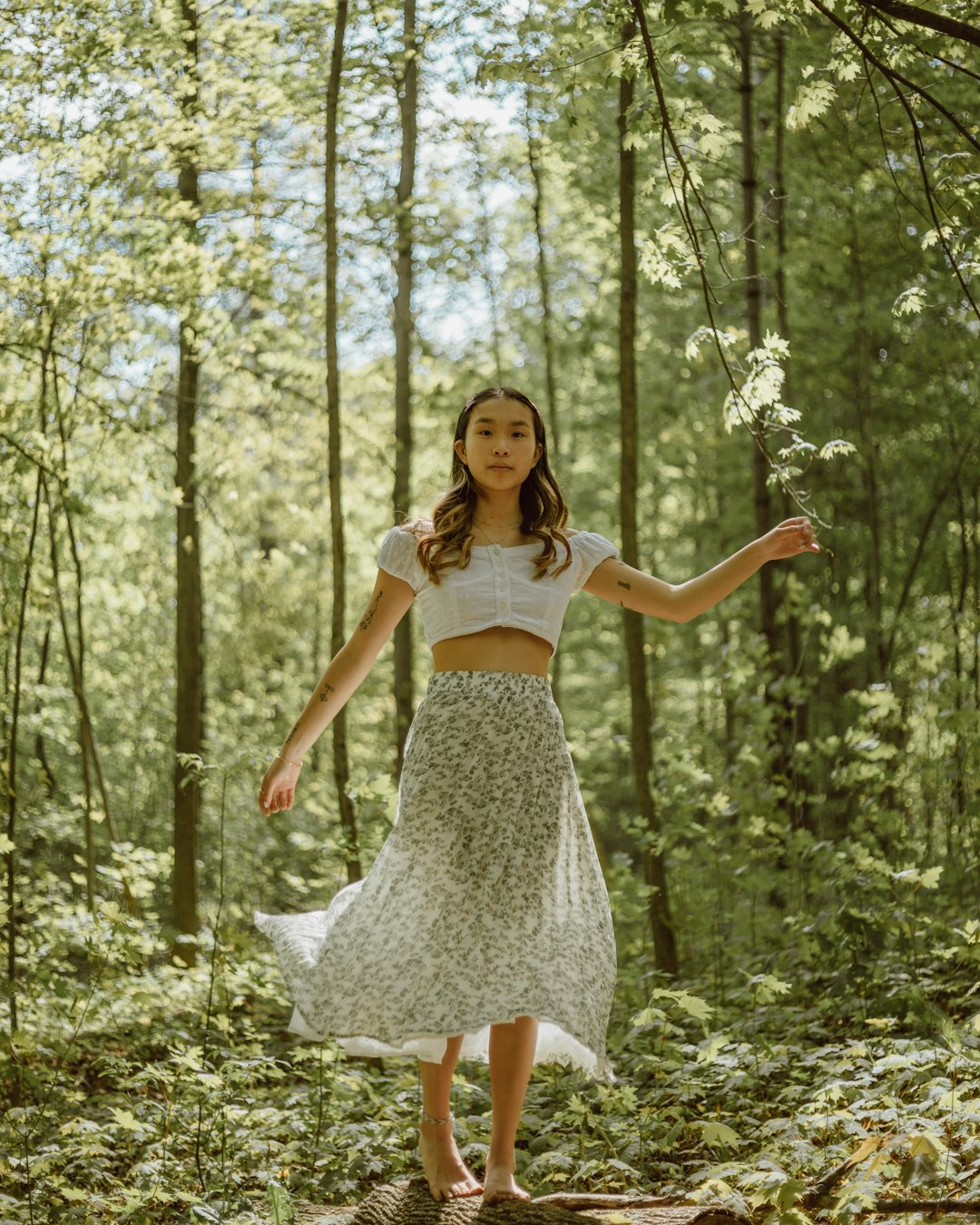 woman in white floral dress standing on forest during daytime