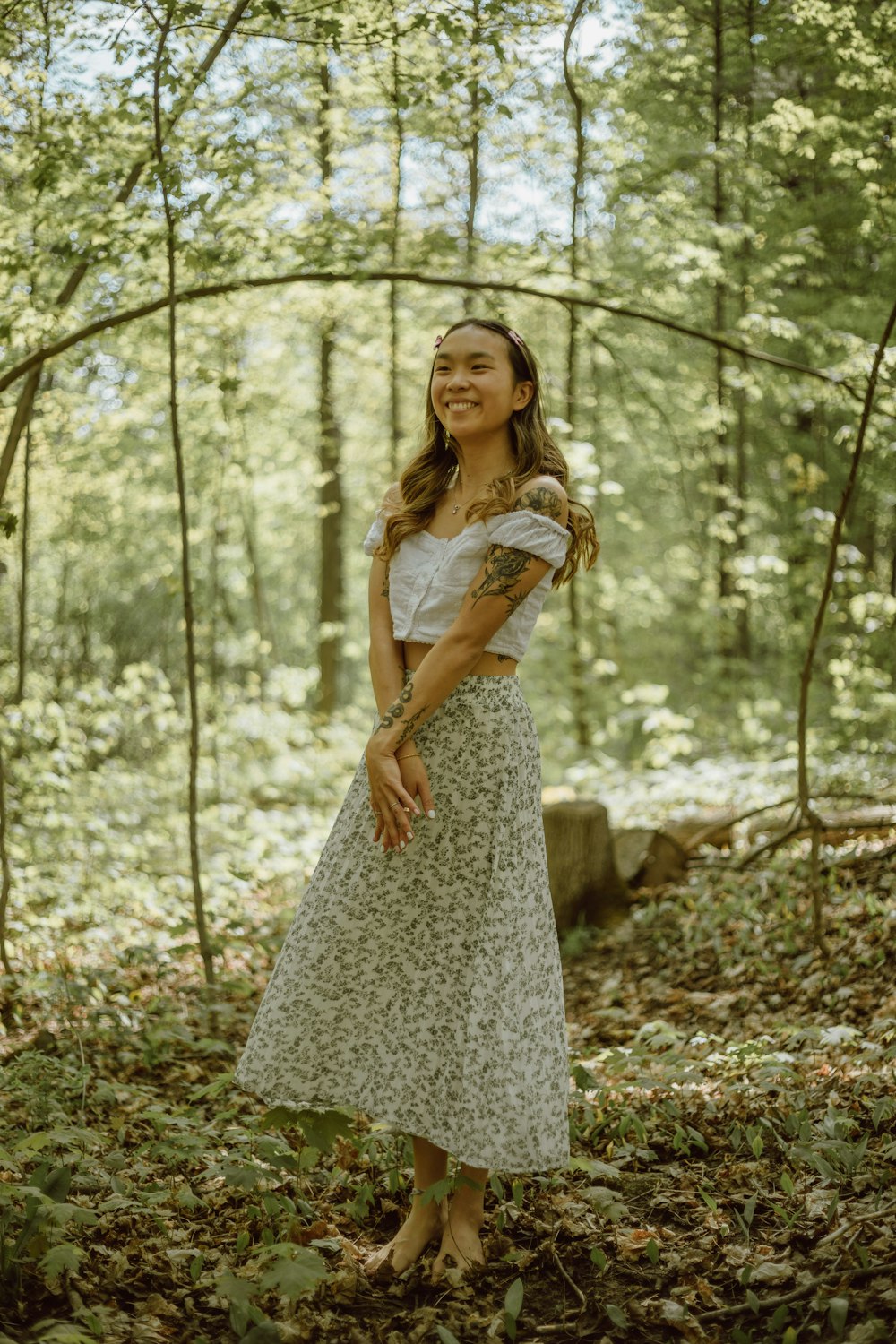 woman in white floral dress standing on forest during daytime