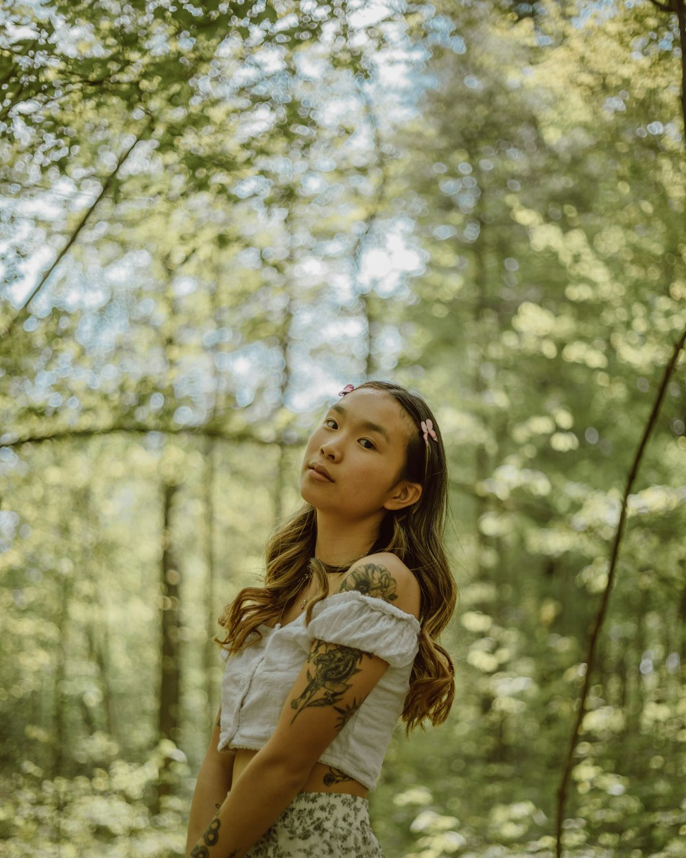 woman in white dress standing near green trees during daytime