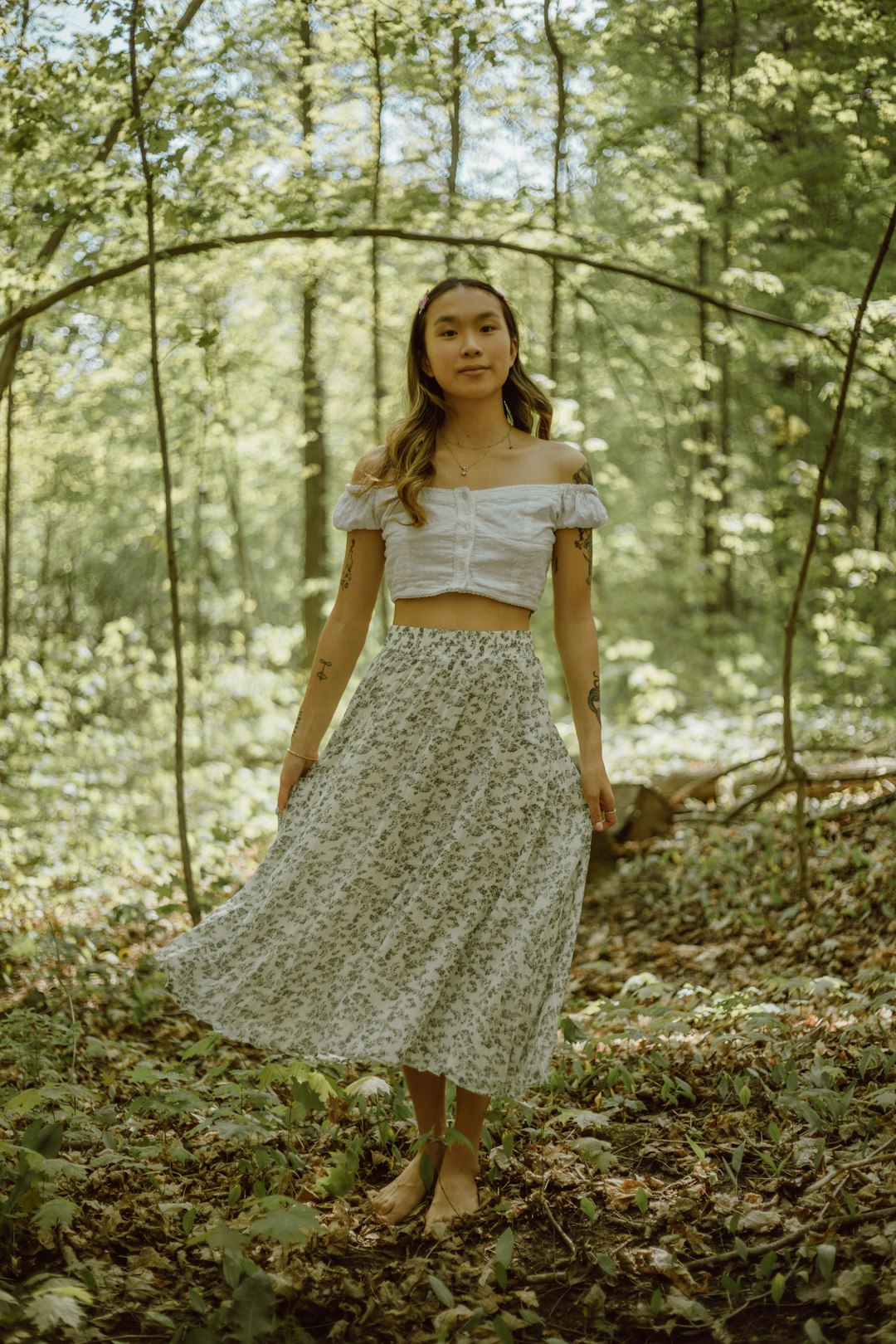 woman in white floral dress standing on forest during daytime