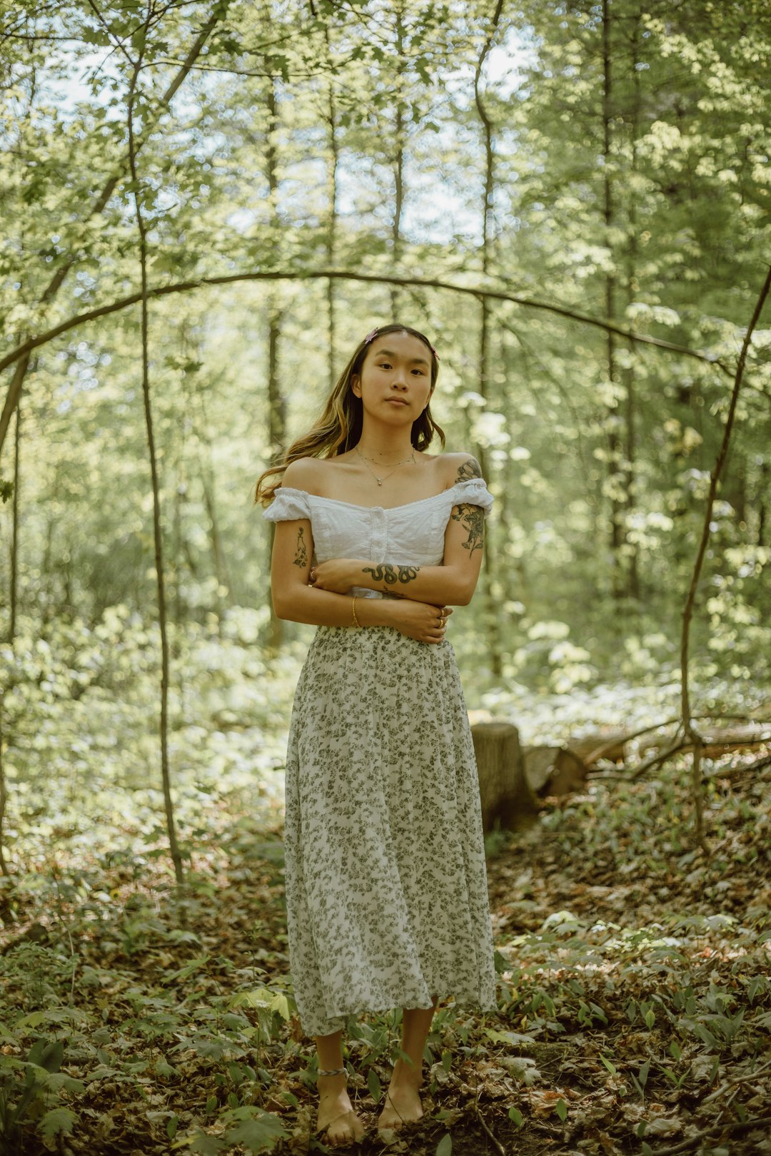 woman in white floral dress standing in forest during daytime