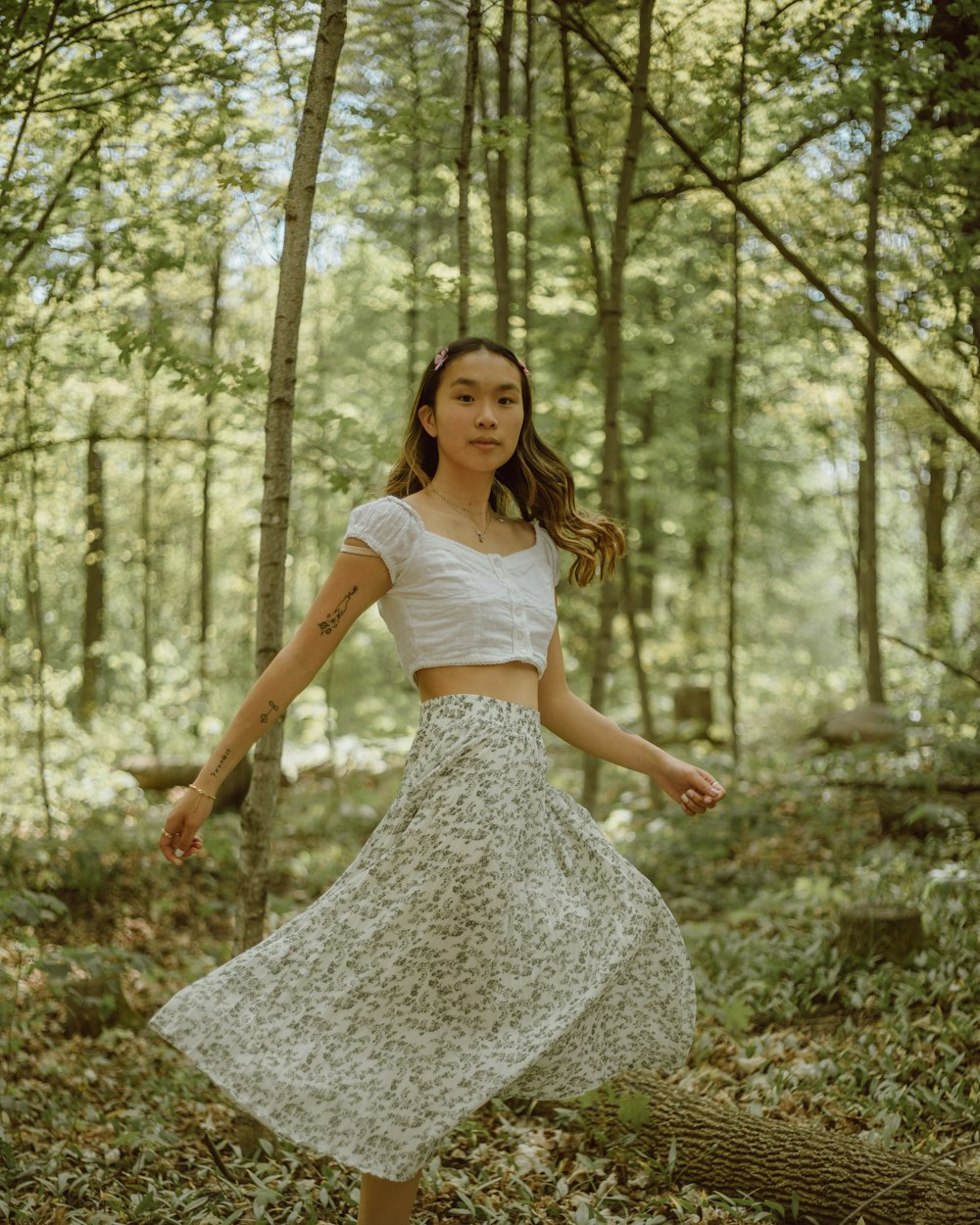 woman in white sleeveless dress standing in forest during daytime