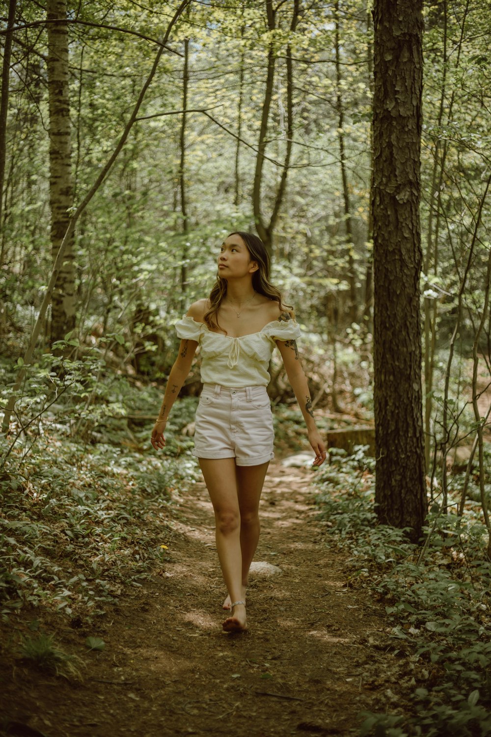 woman in white dress standing on forest during daytime