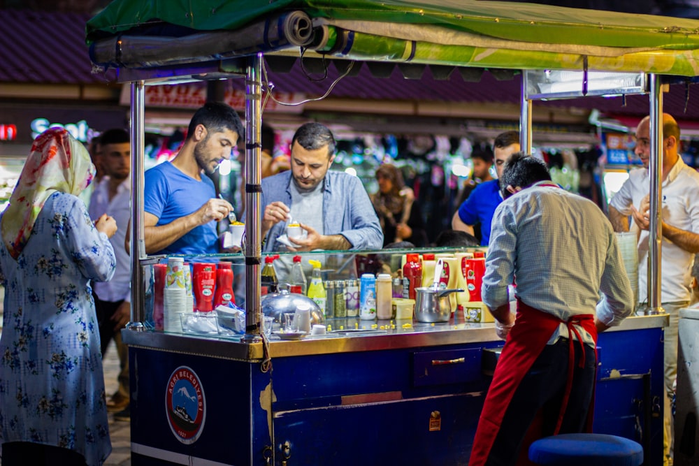 man in white dress shirt standing in front of food stall