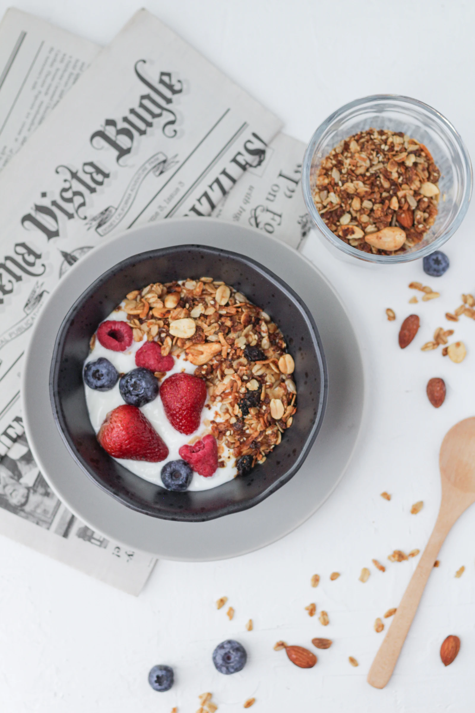 A bowl of yogurt topped with granola, strawberries and blueberries