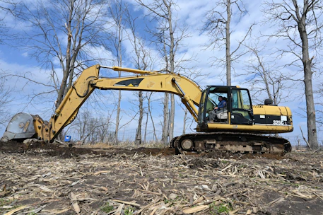 Excavator working on a construction site preparing the ground in a rural area.