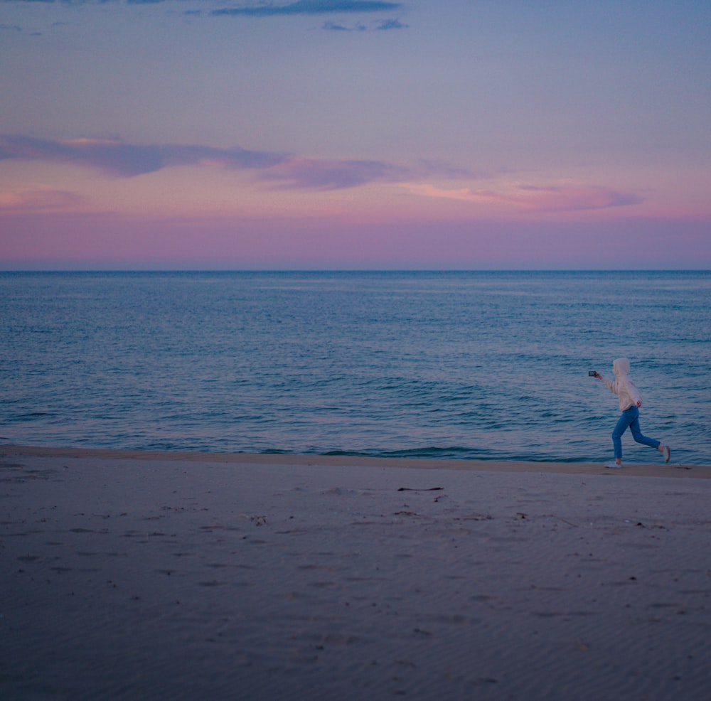 woman in white dress walking on beach during sunset