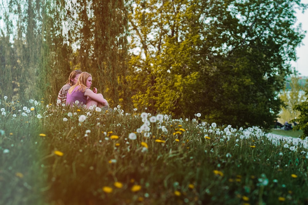 girl in pink dress sitting on white flower field during daytime