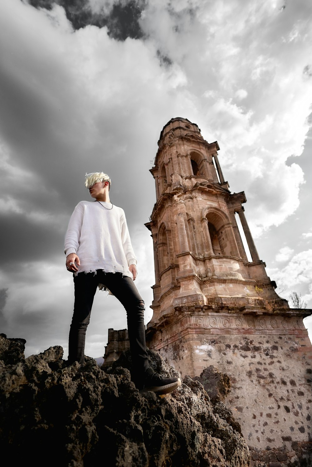 man in white dress shirt and black pants standing on brown rock formation during daytime