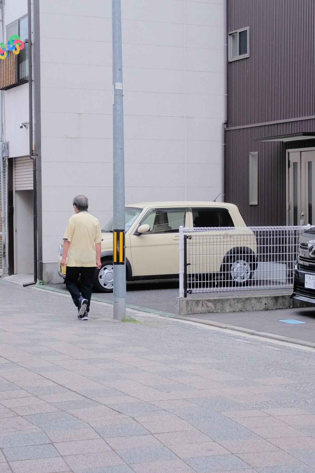 man in yellow shirt and black pants walking on sidewalk during daytime