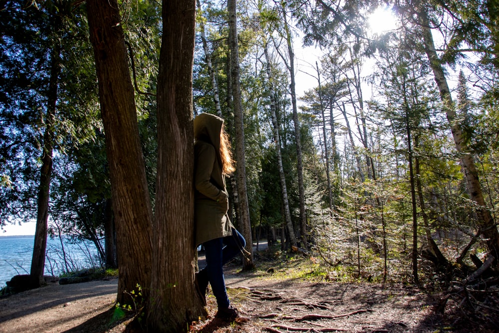 woman in green jacket and black pants walking on forest during daytime