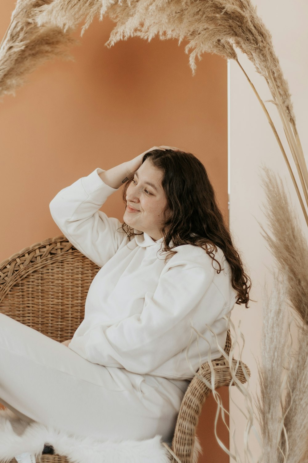 woman in white long sleeve shirt sitting on brown woven chair