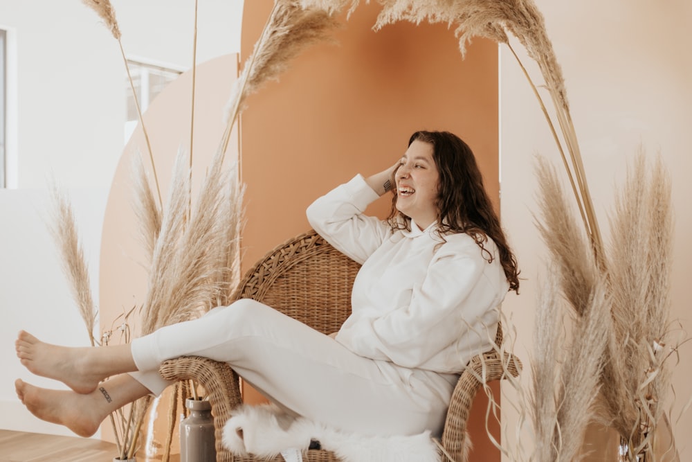 woman in white long sleeve shirt sitting on brown wicker chair