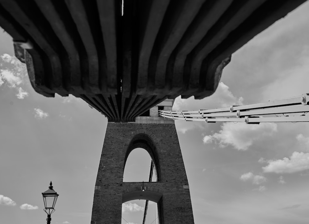 grayscale photo of bridge under cloudy sky