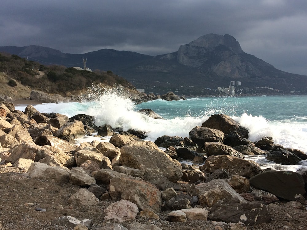 rocky shore with ocean waves crashing on rocks during daytime