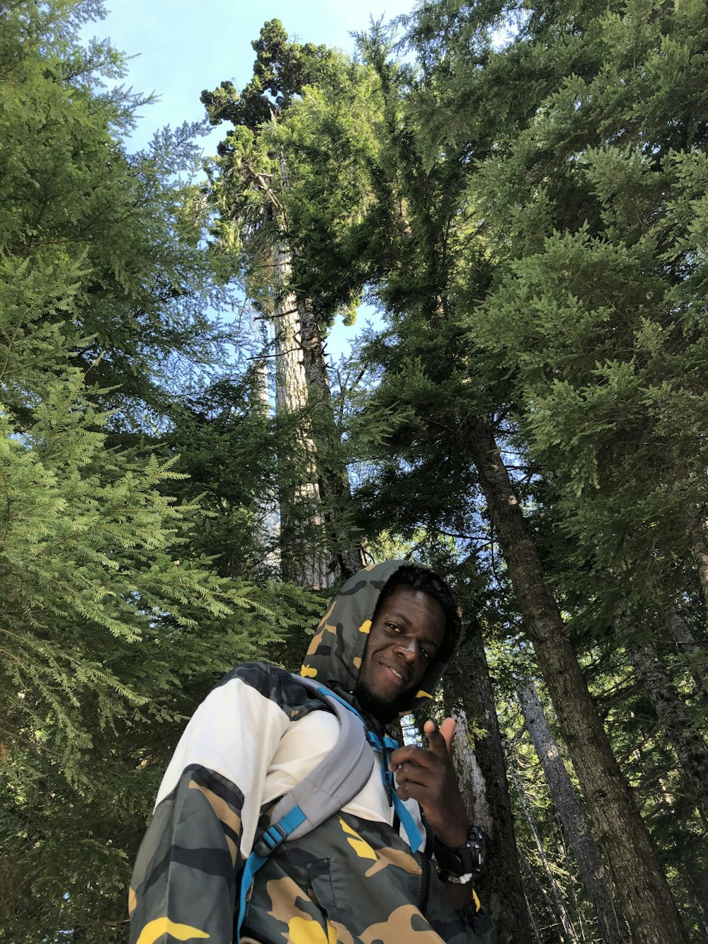 woman in white and blue jacket standing under green trees during daytime