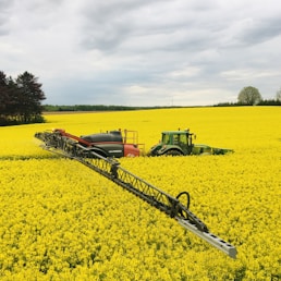 green tractor on yellow flower field during daytime