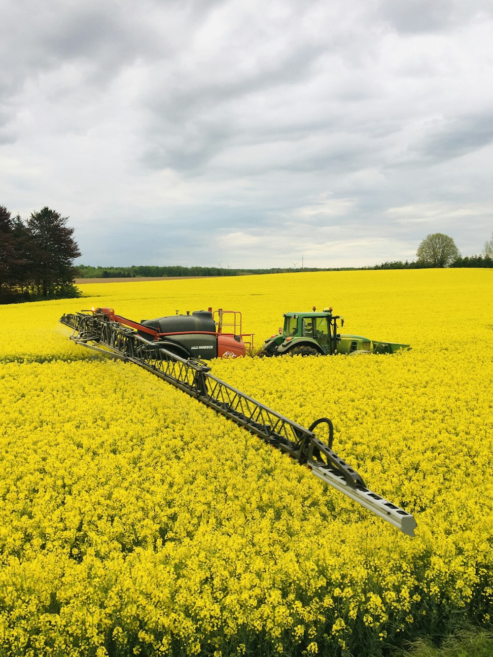Grüner Traktor auf gelbem Blumenfeld tagsüber