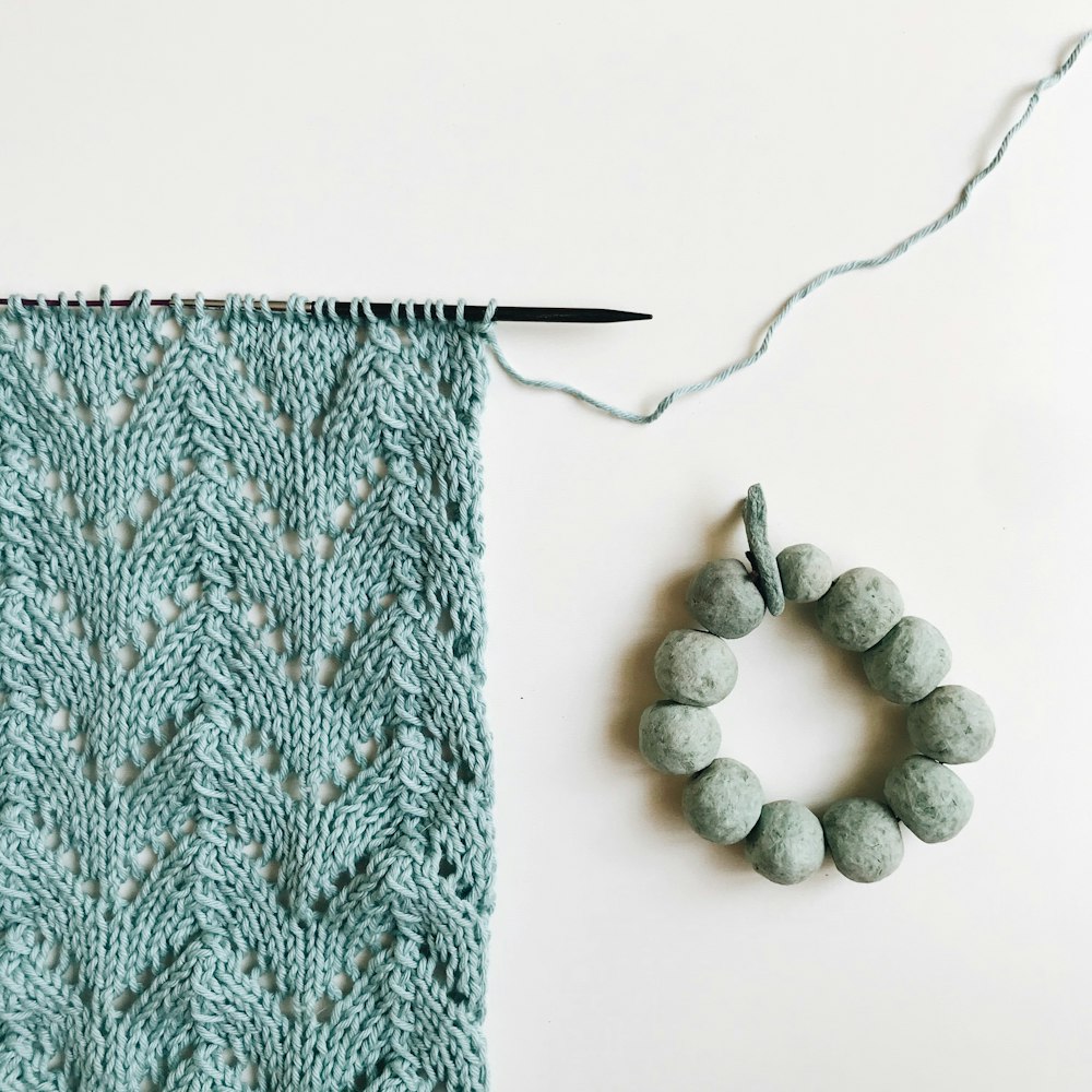 textile tricoté vert à côté de pierres blanches et grises